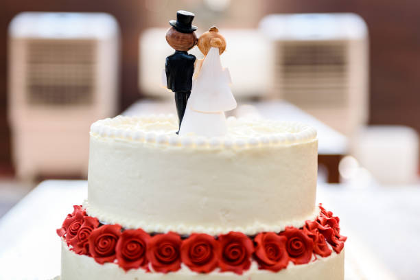 istock White wedding cake with bride and groom figurines on top. 1187593223