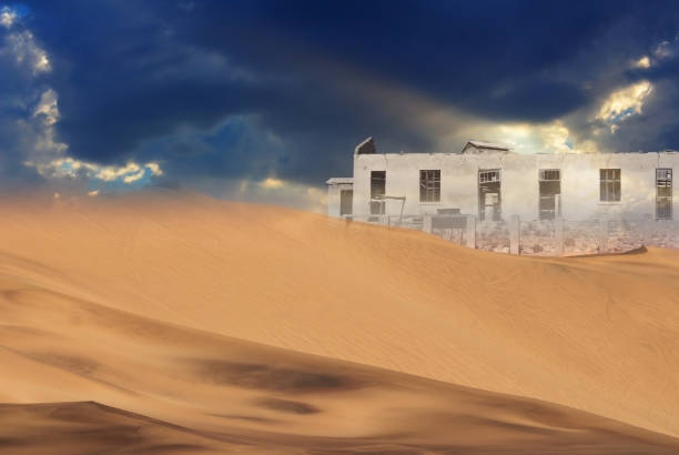 Abandoned house in the desert on the background of sand dunes and dramatic sky Abandoned house in the desert on the background of sand dunes and dramatic sky kolmanskop namibia stock pictures, royalty-free photos & images