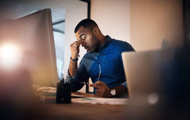 My head feels like it's about to explode Shot of a young businessman looking stressed out while working in an office at night emotional stress stock pictures, royalty-free photos & images