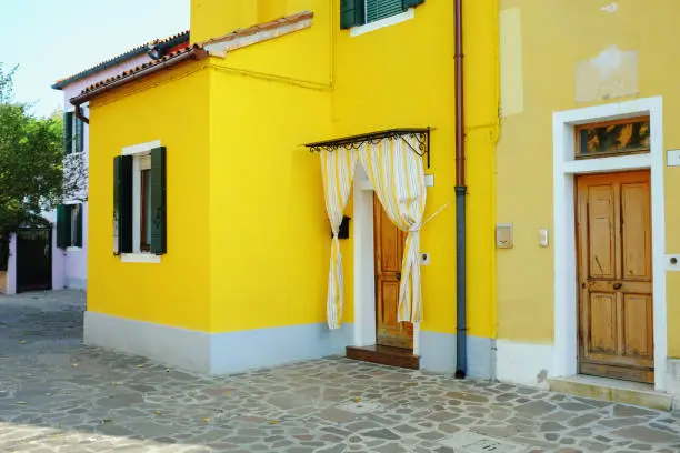 Venice, Italy - 27 October, 2019: traditional house in Burano, Venice, in vibrant yellow colour and curtains