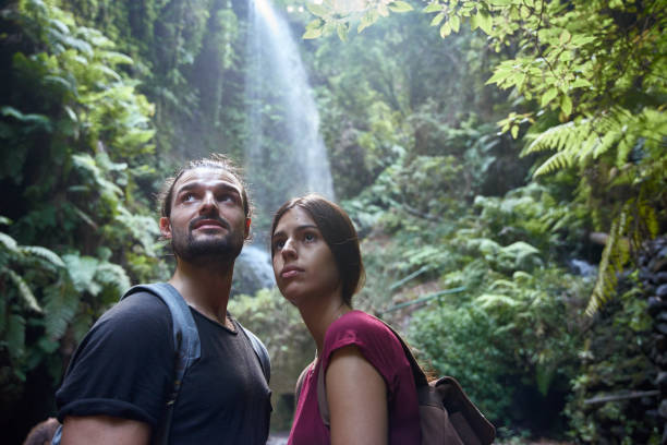 istock Young couple standing in front of a waterfall 1187598062