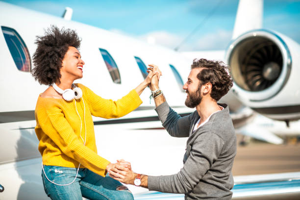 jeunes, jeunes couples à la mode retenant des mains et dansant ensemble le prochain jet privé garé sur un tarmac d'aéroport - status symbol audio photos et images de collection