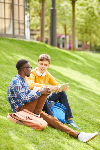Students Sitting on Green Lawn