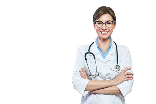 portrait of glad smiling doctor in white uniform standing with crossed hands on blue clinic background - portrait doctor paramedic professional occupation imagens e fotografias de stock