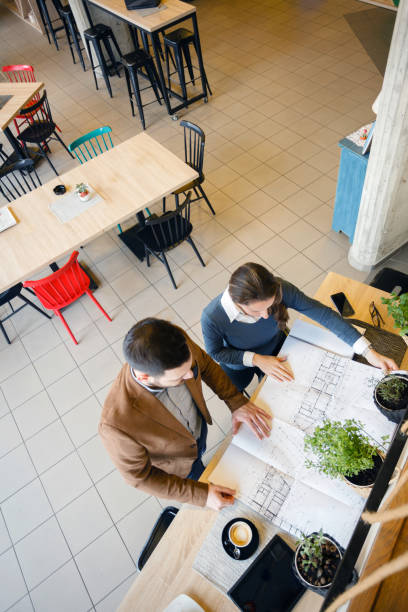 istock Two young architects examining building plans during a meeting in a modern cafe 1187617773
