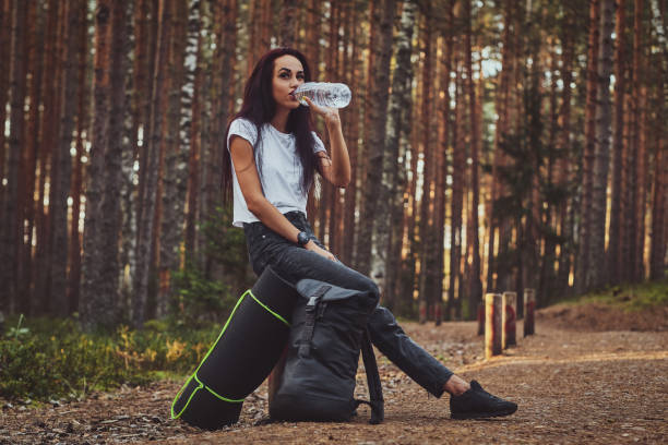 istock Young girl is resting in the forest while drinking water. 1187621994