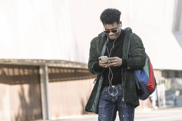 istock african man with earphones texting with a phone 1187628348