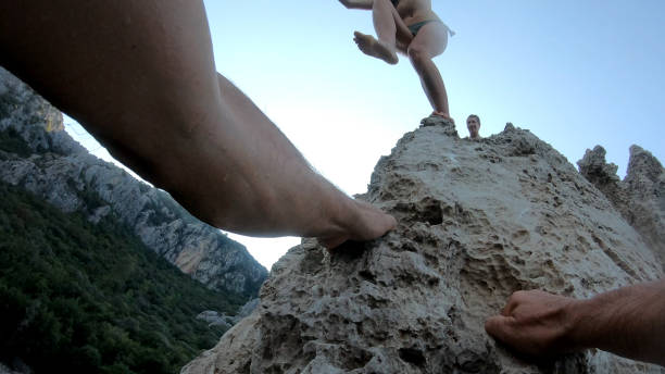 istock POV of man's hands climbing up seaside cliff 1187629806