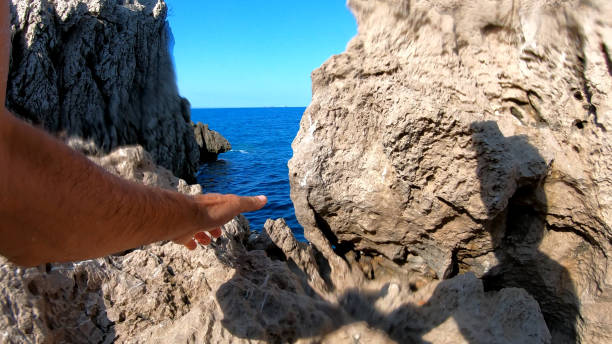 istock POV of man's hands climbing up seaside cliff 1187629967