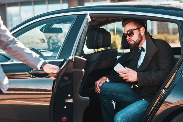 istock Busy nice businessman in sunglasses is talking by smartphone while his elegant assistant is opening door for him. 1187631750
