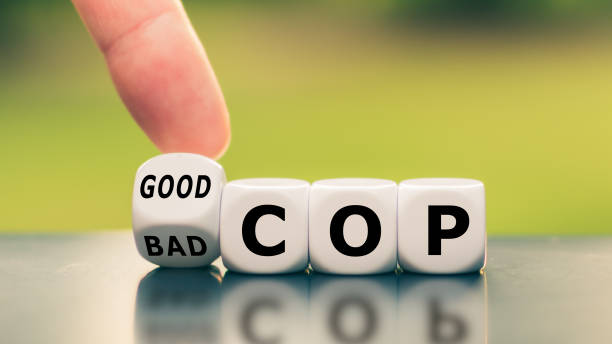 Hand turns a dice and changes the expression "bad cop" to "good cop", or vice versa. stock photo