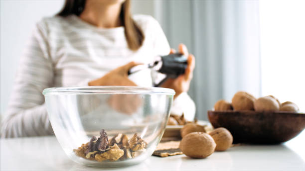 la jeune femme fend une noix et la recueille dans le bol en verre, plan rapproché - indian nut photos et images de collection