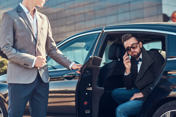 istock Busy businessman in sunglasses is talking by smartphone while his elegant assistant is opening door for him. 1187632461