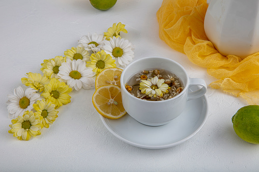 Glass cup with herbal tea with chamomile flowers on a white background. Healthy drink.