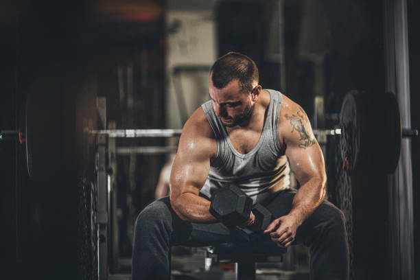 istock Man exercising in gym with dumbbell 1187633691