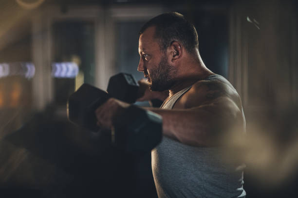 istock Man body builder training in gym with dumbbells 1187635010