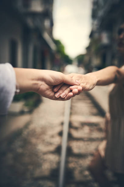 Cropped shot of a couple holding hands while walking on the train tracks in Vietnam