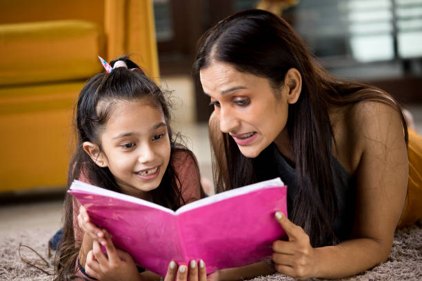 istock Mother with her daughter reading book at home 1187639137