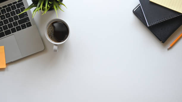 istock Tabletop office desk with laptop, notebook, pencil, plant with white table. 1187640031