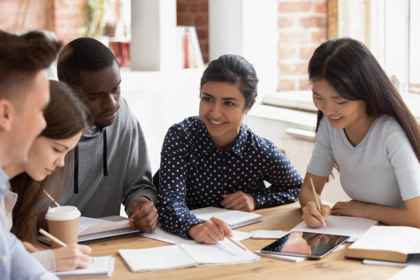 istock Focused multi national students sitting at desk studying together 1187643075