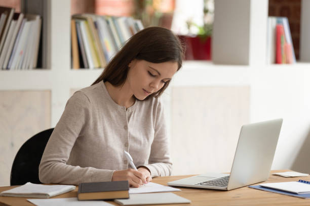 istock Woman studying sitting at library table preparing for entrance exams 1187643107