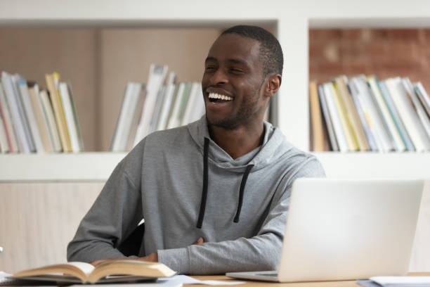 étudiant africain accomplir le travail regardant loin bavardant avec des amis - desk men bizarre classroom photos et images de collection