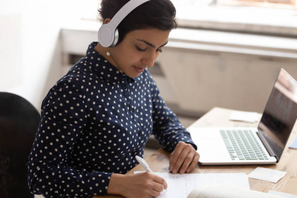 etnia india mujer usando auriculares escucha curso educativo estudiando en línea - online degree fotografías e imágenes de stock