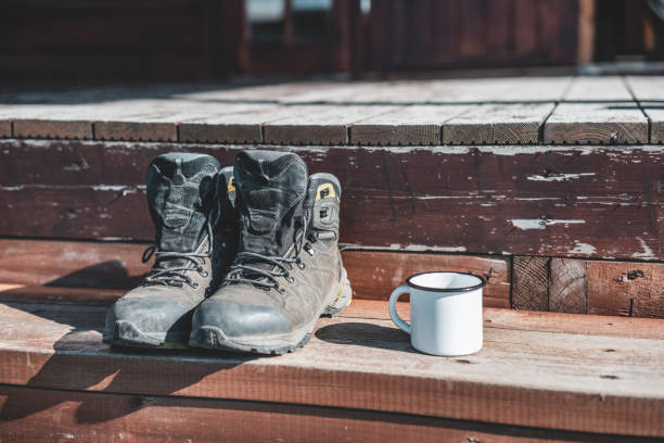 The white enamel mug and trekking shoes on the wooden porch.