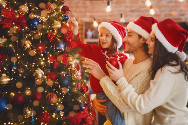 Photo of Happy family decorating xmas tree with bubbles at home