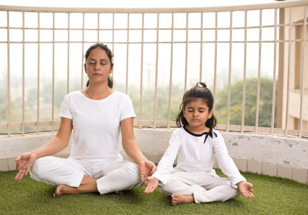 istock Mother with daughter meditating in lotus position 1187647075