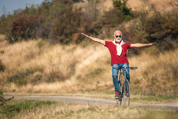 istock Senior man riding a bicycle with arms outstretched. 1187647217