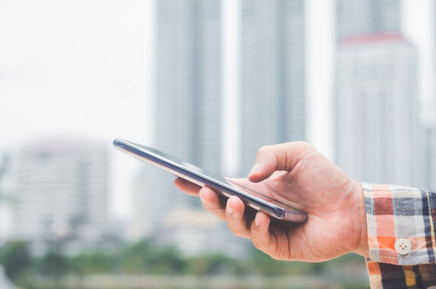 istock close up handsome businessman using hand typing smartphones and touch screen working search with app devices outdoor in city with sunrise and building background. 5G technology connecting the world. 1187647638