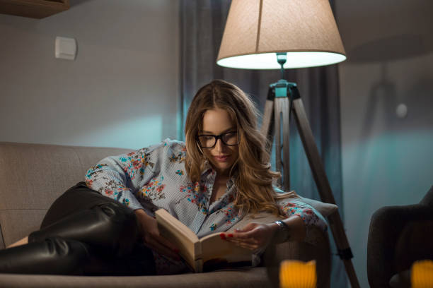 Young female reading book in living room stock photo
