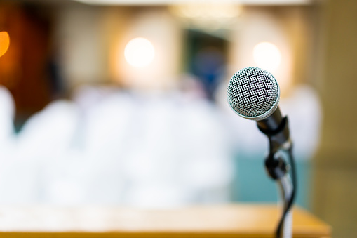 Wired microphone set up on the front of conference room close up with blurred background.  Wired microphone close up with copy space background.