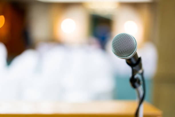 Microphone on stage close up. Wired microphone set up on the front of conference room close up with blurred background.  Wired microphone close up with copy space background. business conference photos stock pictures, royalty-free photos & images