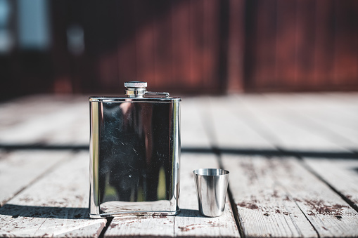 A metal flask on a wooden porch in the sun