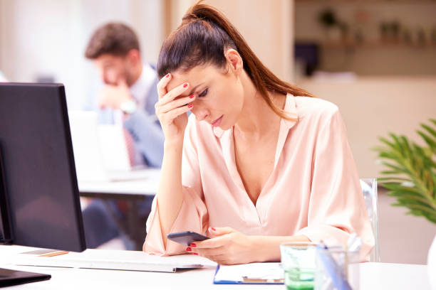 istock Serious faced businesswoman text messaging at office desk 1187648920