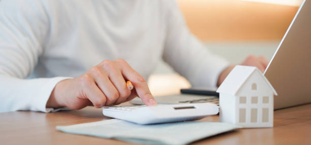 close-up jonge man handdruk op calculator om te controleren en samenvatting kosten van hypothecair krediet hypotheek voor herfinancierings plan, people lifestyle concept - rental stockfoto's en -beelden