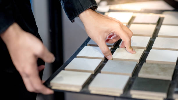 Choosing ceramic sample from swatch board Male architect or interior designer hand choosing ceramic texture sample from swatch board in design studio. Floor and wall finishing material for architecture and construction industry. tiled floor stock pictures, royalty-free photos & images