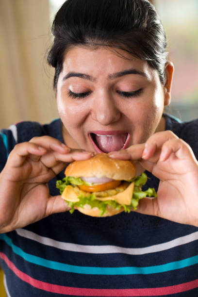 istock woman eating a fast food burger 1187663977