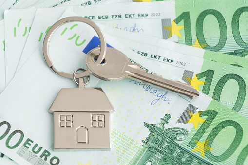Home keys and a small house on currencies euro background. The concept of renting or selling house or flat, mortgage, investment or real estate, property buying. Money for the housing plan.