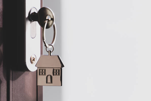 the home key with house keyring in the door keyhole with copy space. the concept of renting or selling a house or flat, mortgage and real estate, property buying - key real estate key ring house key imagens e fotografias de stock