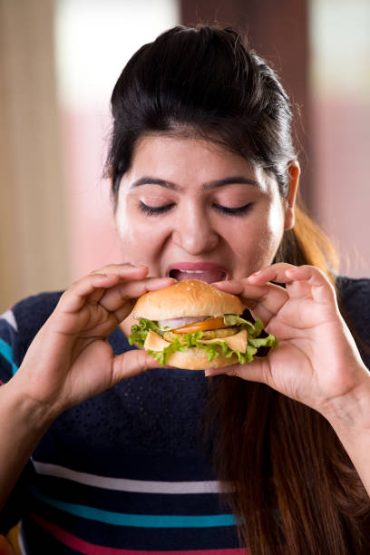 istock woman eating a fast food burger 1187664220