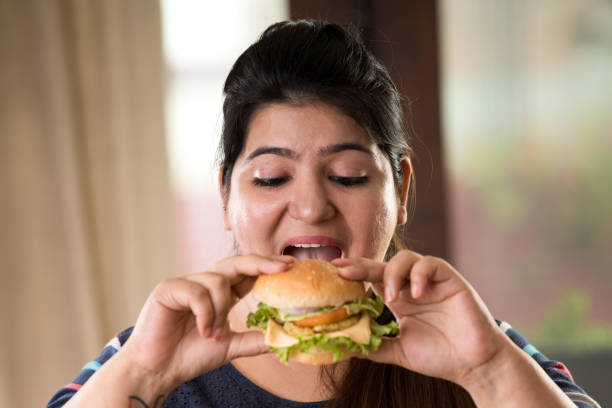 istock woman eating a fast food burger 1187664298