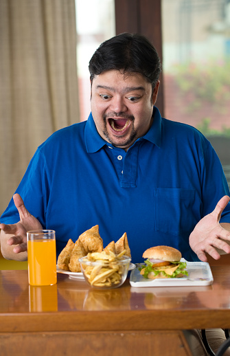 Excited fat man holding a plate full of unhealthy samosa