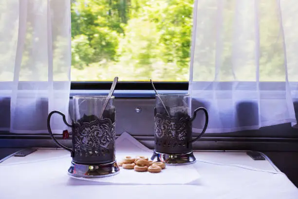 A table in the cab of the train with glasses, spoons and steering-wheel.