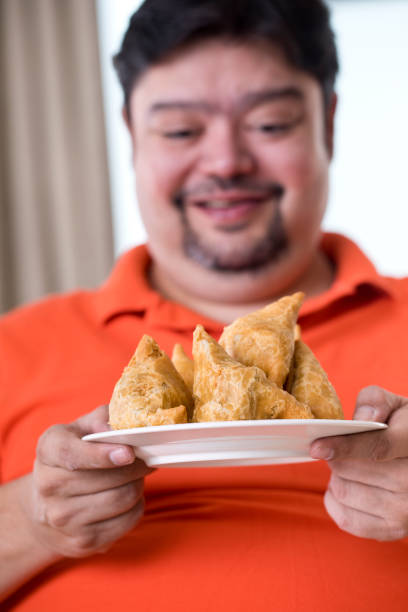 istock Overweight man holding fried samosa 1187667819