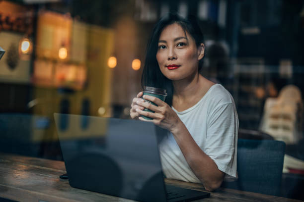 istock Beautiful woman drinking coffee and using laptop 1187668046