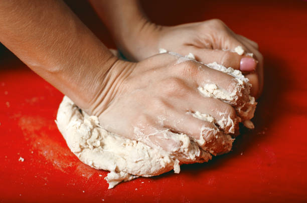istock female hands in flour closeup kneading dough on table 1187668469