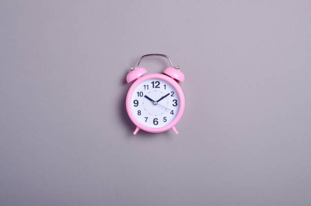 istock Modern pink alarm clock on gray background 1187668478